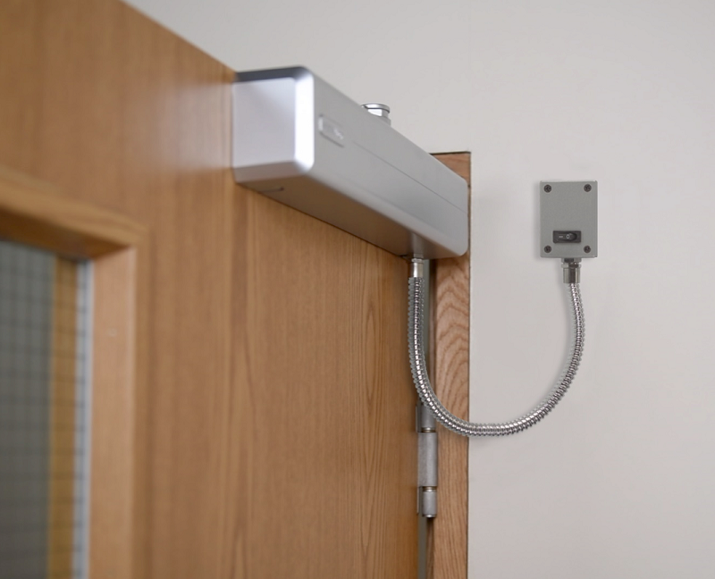Products which hold doors open automatically are widely used to limit the number of people touching doors in high-traffic areas. Image courtesy of ASSA ABLOY